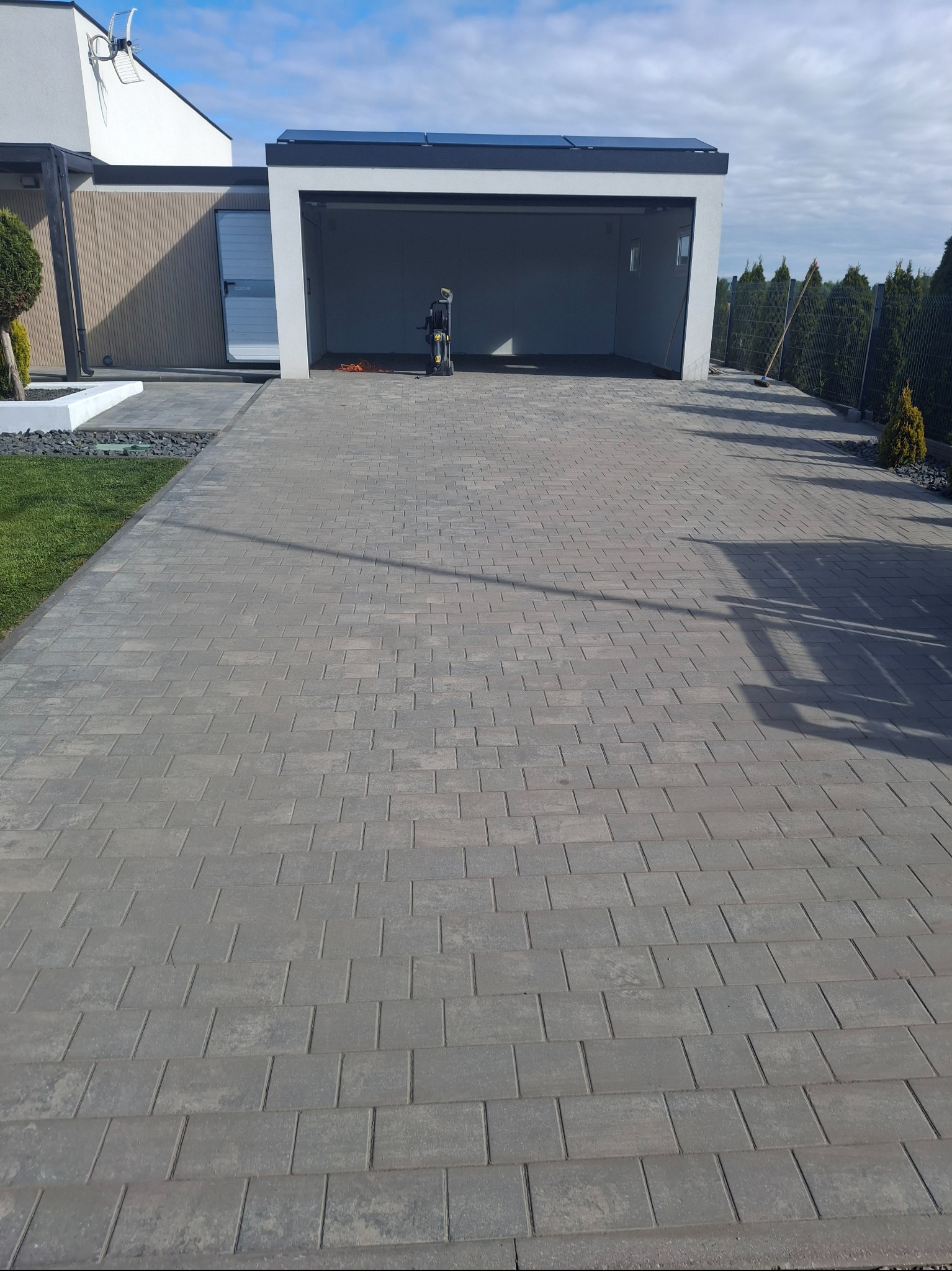 Kostka brukowa na podjeździe do garażu, widoczna myjka ciśnieniowa. Czysta powierzchnia, nowoczesny design.