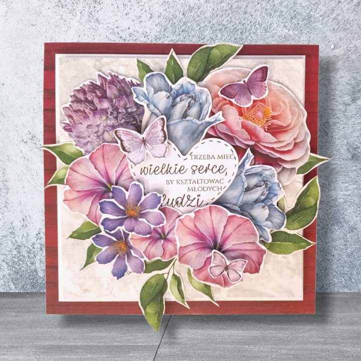 Ręcznie robiona kartka okolicznościowa w kwadratowej ramce, z kompozycją kwiatową w odcieniach różu, fioletu i błękitu, ozdobiona motylami i sercem z napisem 'Trzeba mieć wielkie serce, by...