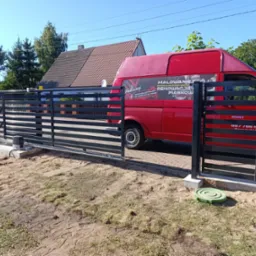 Nowoczesna brama wjazdowa przesuwna z poziomymi panelami w Nowogardzie, częściowo otwarta. W tle czerwony van z reklamą firmy. Słoneczny dzień.