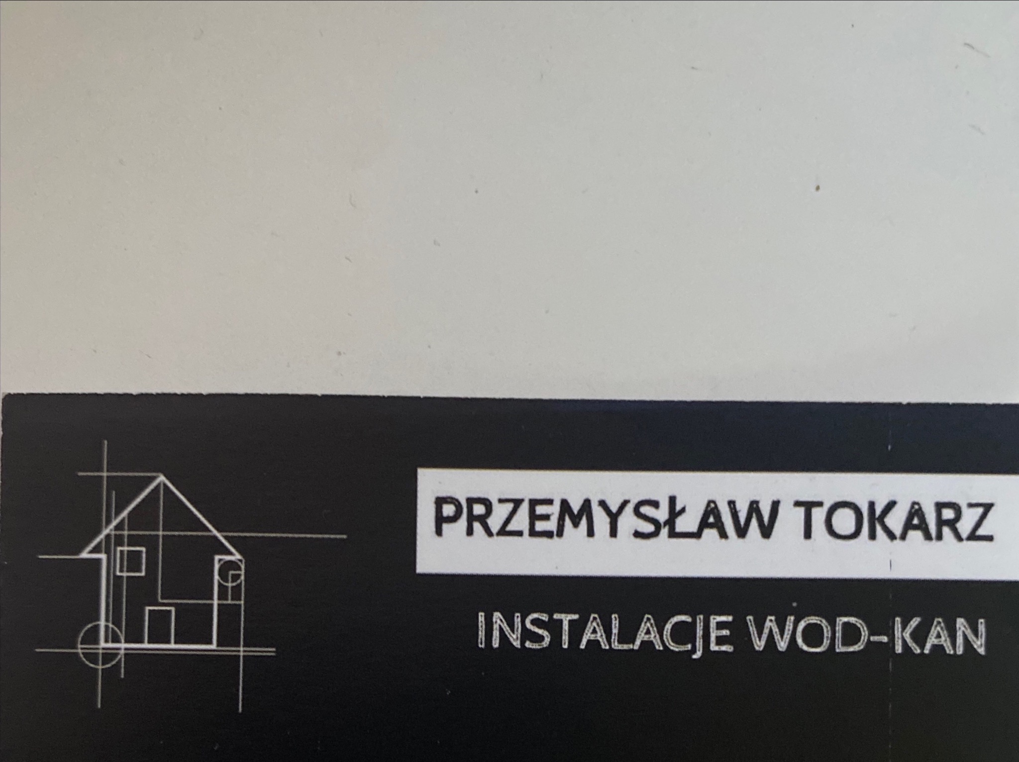 Wizytówka firmy Przemysław Tokarz, specjalizującej się w instalacjach WOD-KAN, z graficznym logo przedstawiającym schemat domu w stylu technicznym.