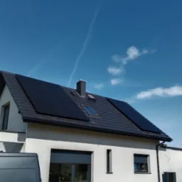 Nowoczesny dom z szarym dachem i panelami słonecznymi na dachu, widok z dołu w słoneczny dzień z lekkimi chmurami i śladami kondensacji po samolotach.