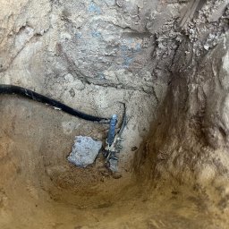 Sebastiansak - Uziemienie w wykopie wypełnionym piaskiem; widoczny przewód uziemiający i złącze z metalową szpilką wbite w ziemię.