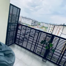 Nowoczesne, drewniane osłony balkonowe z poziomych listew w kolorze ciemnego brązu, widok z balkonu na osiedle mieszkaniowe w pochmurny dzień.