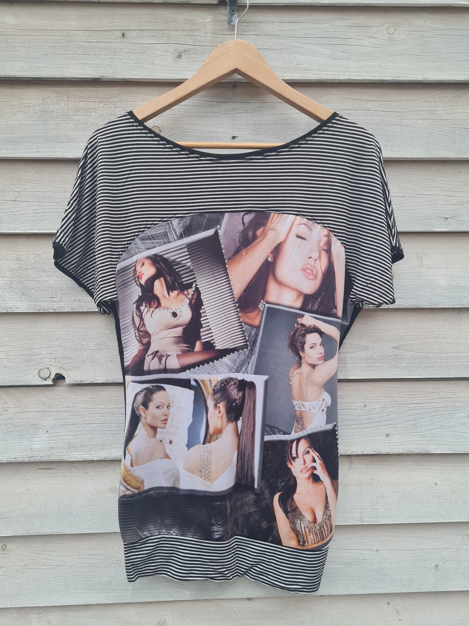 Używana bluzka w paski z nadrukiem kolażu zdjęć kobiety, prezentowana we Wrocławiu na drewnianym wieszaku przed jasną, drewnianą ścianą.