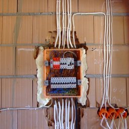 E .L .E .S . Instalacje elektryczne - Rozdzielnica elektryczna w trakcie montażu w Głogowie. Widoczne przewody i zabezpieczenia na tle ceglanej ściany. Instalacja w trakcie prac, pianka montażowa.