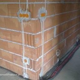 ELES Bud-System - Instalacja elektryczna w surowym murze z cegły ceramicznej. Widoczne kable w peszlach, puszki instalacyjne. Etap prac przed tynkowaniem.