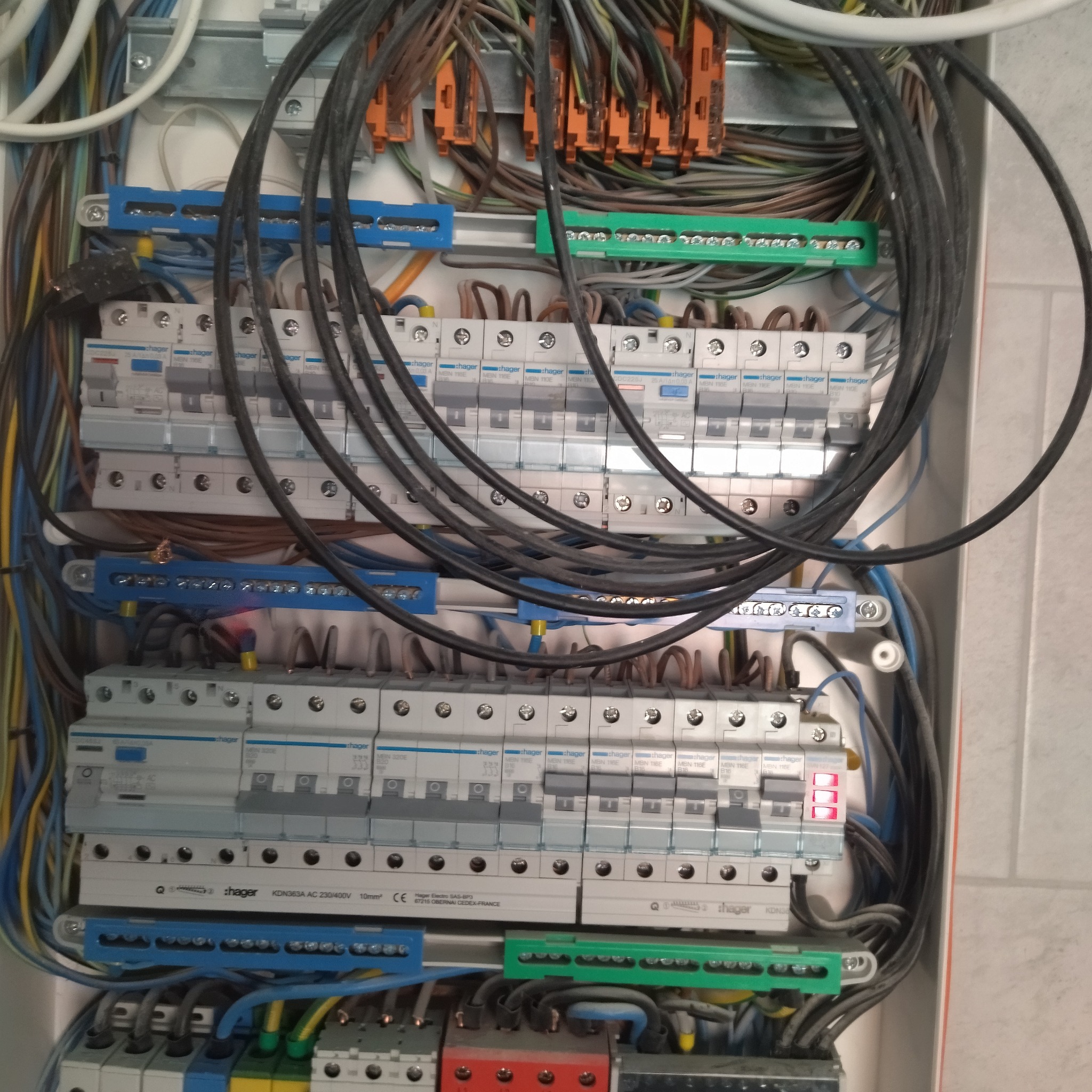 Rozdzielnica elektryczna po montażu. Widoczne zabezpieczenia, przewody i listwy zaciskowe. Jeden z wyłączników oznaczony czerwoną diodą.