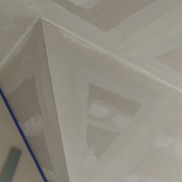 Regimex licencjonowany wykonawca firmy RIGIPS Polska. - Sufit z płyt kartonowo-gipsowych w trakcie szpachlowania, widoczne łączenia płyt z taśmą i szpachlą, fragment ściany z niebieską taśmą malarską.