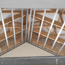 Regimex licencjonowany wykonawca firmy RIGIPS Polska. - Montaż metalowej konstrukcji pod zabudowę poddasza w Bierutowie, widoczne krokwie i częściowo zamontowana izolacja.