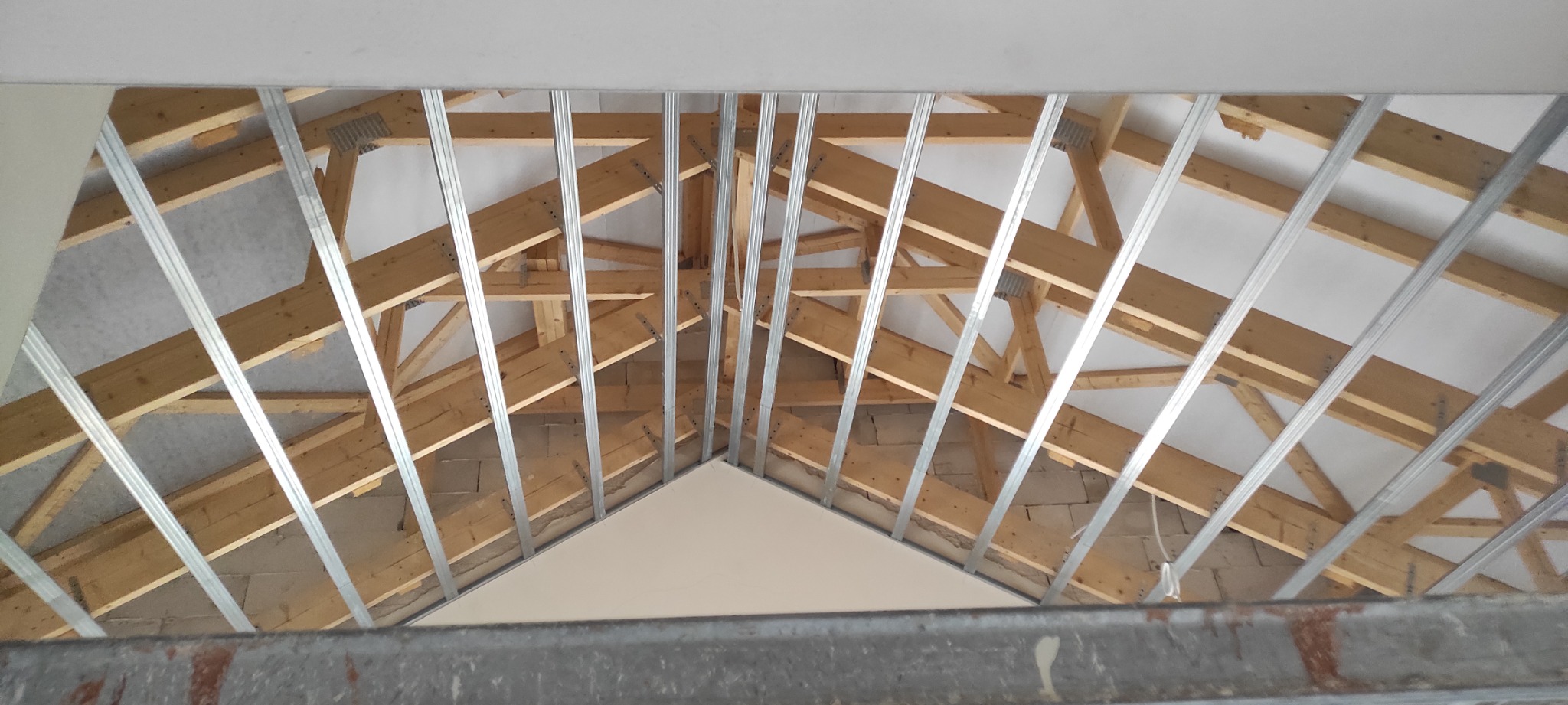 Montaż metalowej konstrukcji pod zabudowę poddasza w Bierutowie, widoczne krokwie i częściowo zamontowana izolacja.