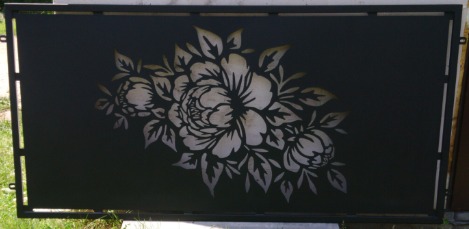 Czarny panel metalowy z wyciętym laserowo motywem kwiatowym, widoczne spawane łączenia ramy. Dekoracyjny element ogrodzenia.
