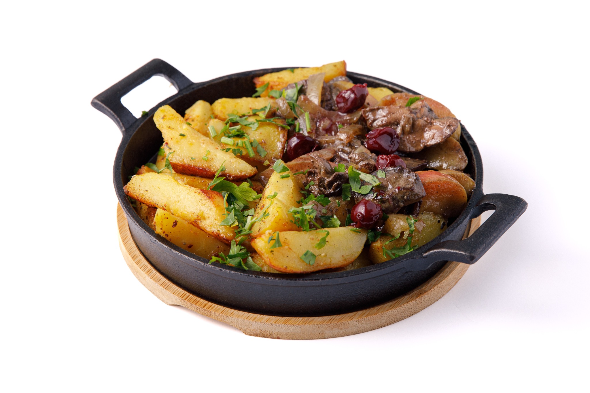 Pieczone ziemniaki z mięsem i żurawiną, posypane świeżą pietruszką, podane w czarnej, żeliwnej patelni na drewnianej podkładce, na białym tle.