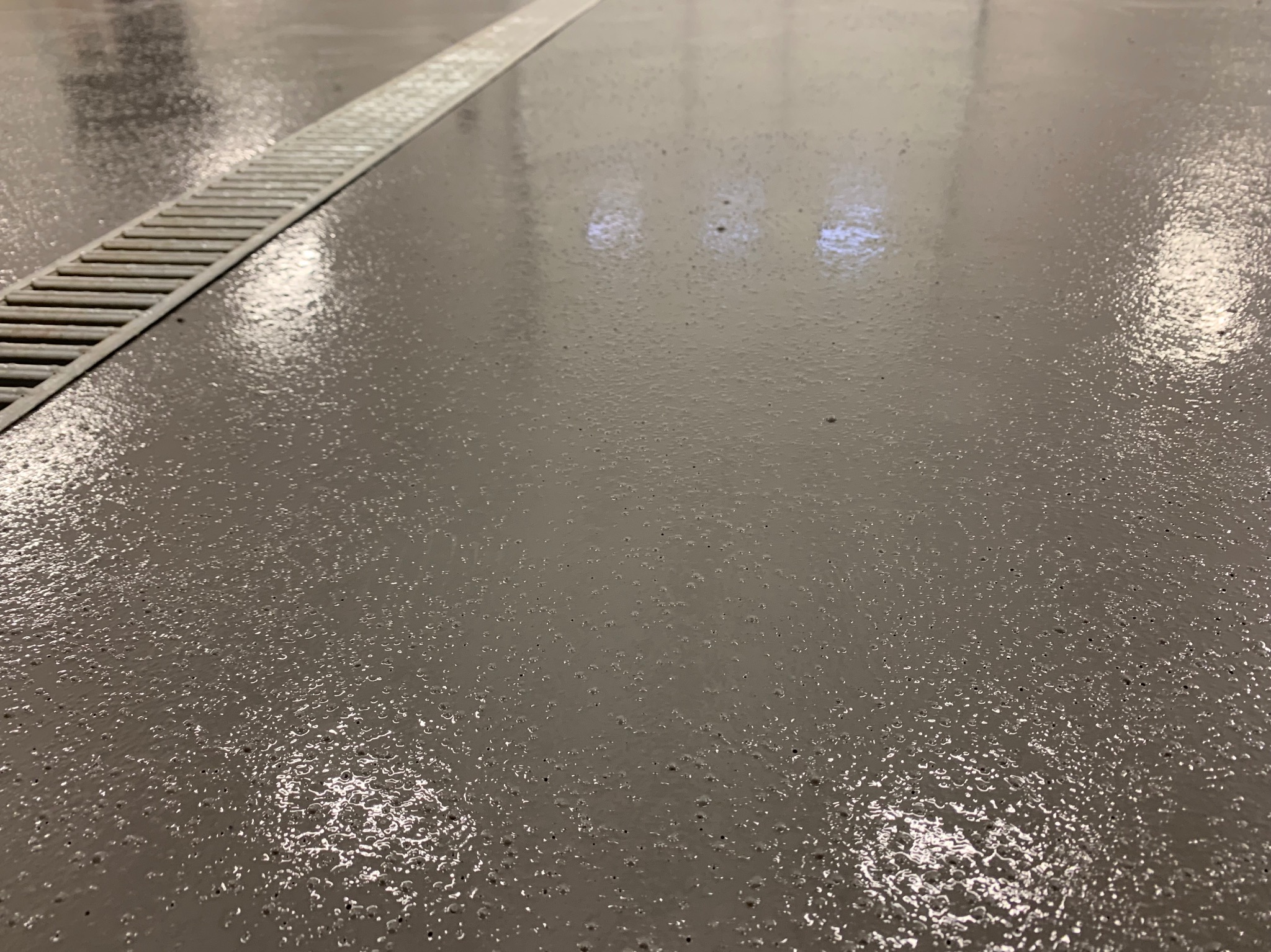 Gładka, szara powierzchnia z odpływem liniowym, lekko odblaskowa, z widoczną strukturą.