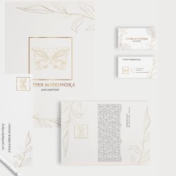 Karolina Bomba digital - Zestaw identyfikacji wizualnej salonu kosmetycznego: wizytówki, papier firmowy i karta z motywem motyla i roślinnymi zdobieniami w kolorze złota.