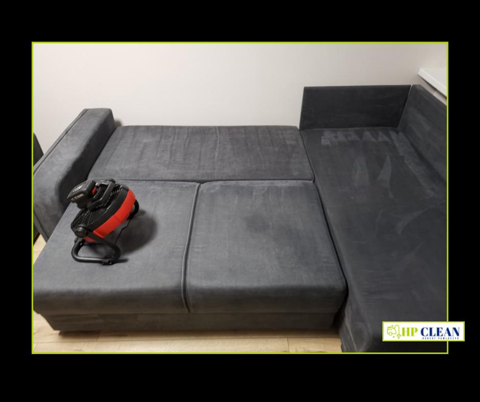 Szara, rozłożona sofa narożna z widocznym wentylatorem wspomagającym suszenie tapicerki po czyszczeniu, na jasnej podłodze.