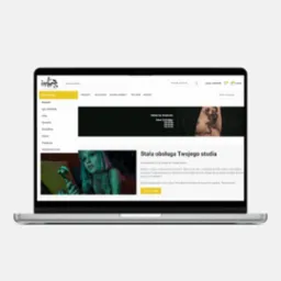Laptop wyświetla stronę internetową studia tatuażu z blondwłosą modelką i ofertą stałej obsługi.