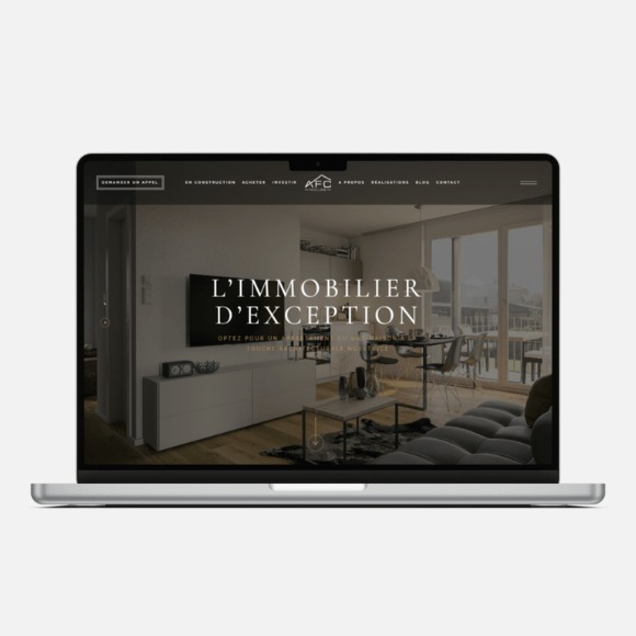 Laptop wyświetlający stronę internetową z minimalistycznym designem wnętrza mieszkania i napisem 'L'IMMOBILIER D'EXCEPTION'.