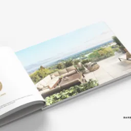 Rozkładówka katalogu prezentująca wizualizację tarasu z widokiem na miasto i rzekę, z meblami ogrodowymi i roślinami, na białym tle, z logo studia graficznego.