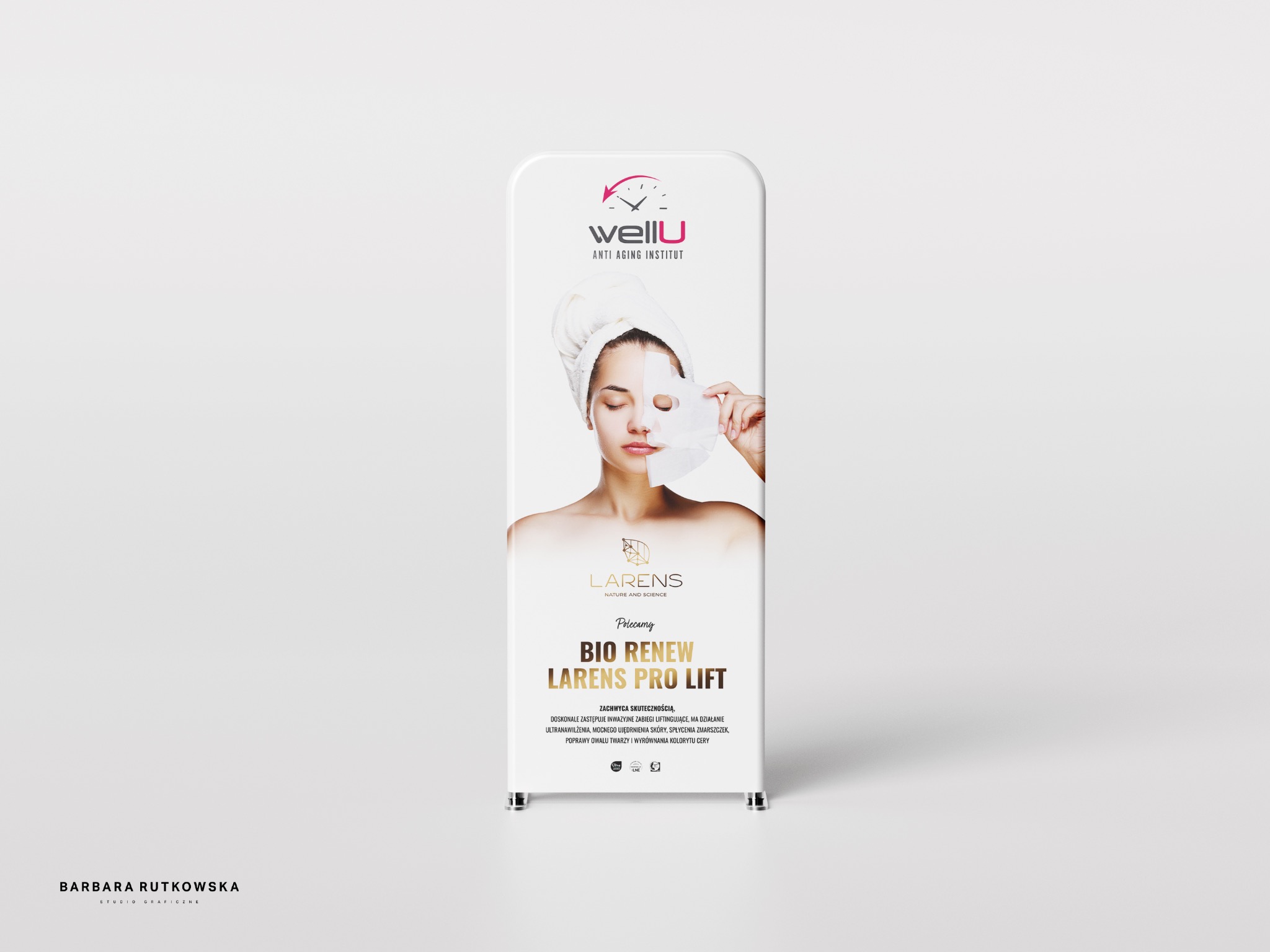 Roll-up reklamowy prezentujący markę WellU Anti Aging Institut oraz produkt Larens Pro Lift Bio Renew, z wizerunkiem kobiety z ręcznikiem na głowie, aplikującej maskę na twarz.