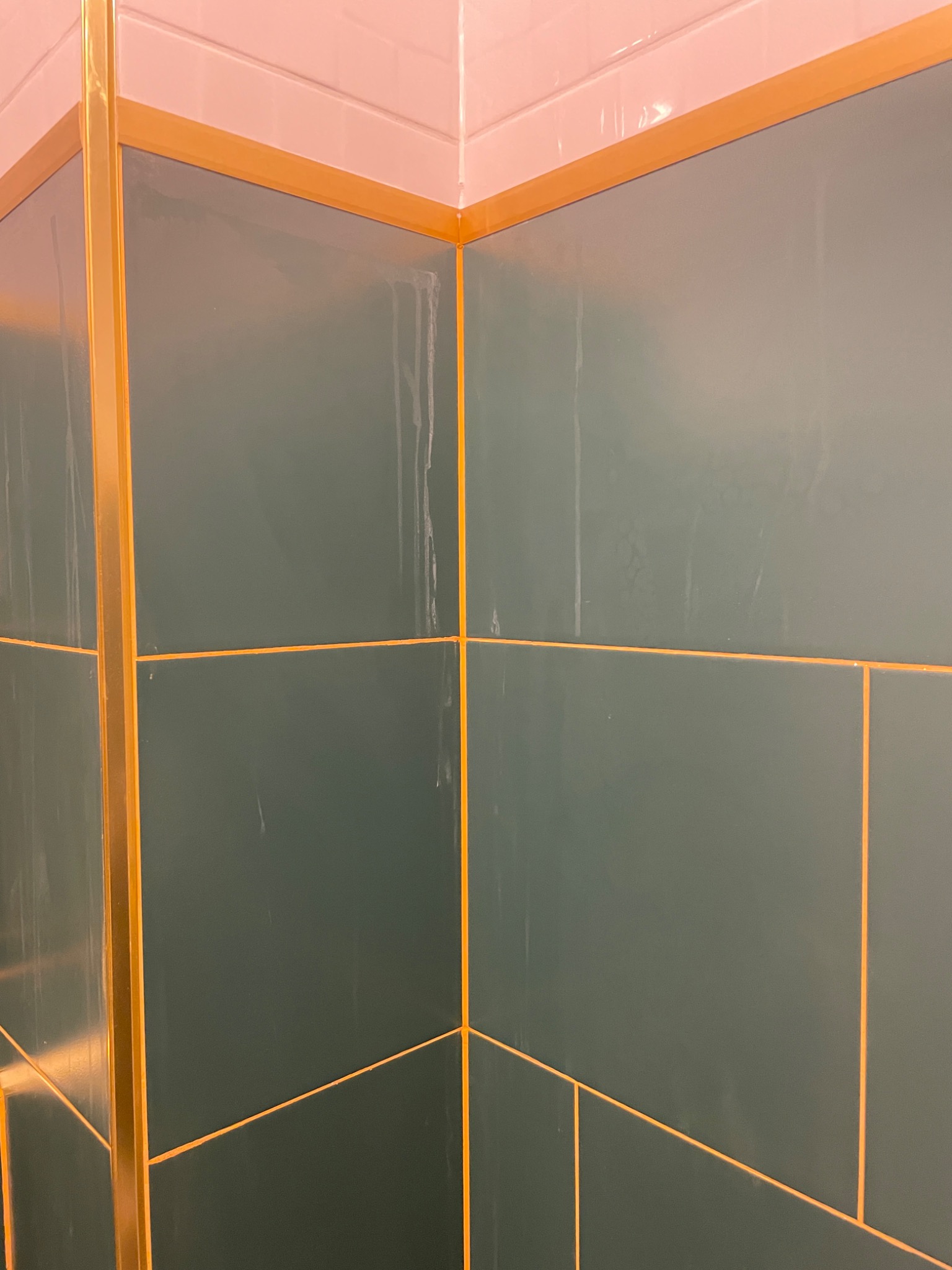 Świeżo położone, ciemnozielone płytki z złotą fugą i złotymi listwami w łazience we Wrocławiu, widoczne ślady po myciu.