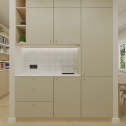 Poligon Design Tomasz Ciurka - Jasna kuchnia z beżowymi szafkami, białymi płytkami i drewnianymi elementami. W tle stół jadalny i okno z widokiem na zieleń. Minimalistyczny design.