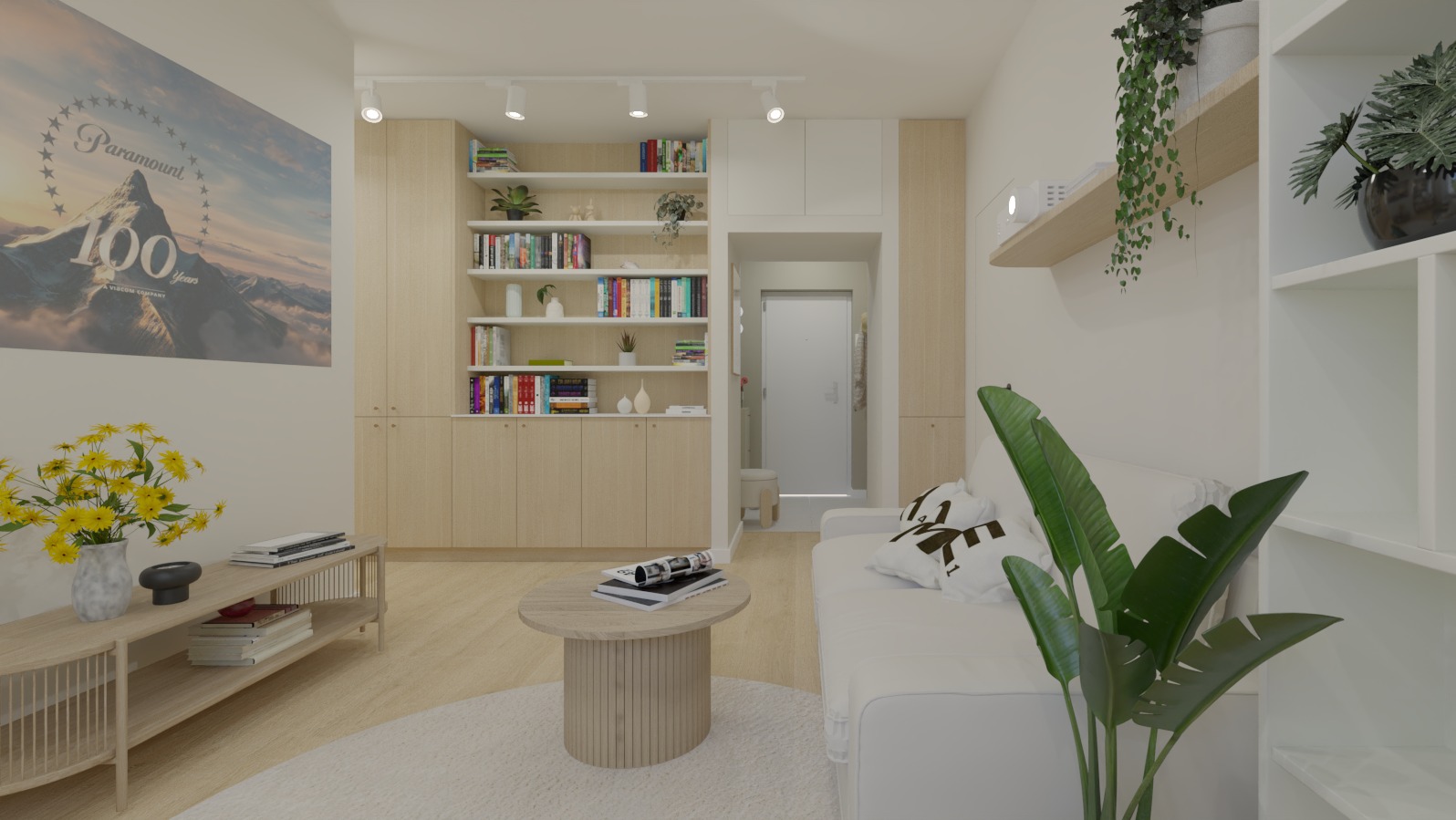 Jasne wnętrze salonu z zabudowaną biblioteczką, okrągłym stolikiem kawowym i białą sofą z dekoracyjnymi poduszkami. Na ścianie plakat z motywem górskim.