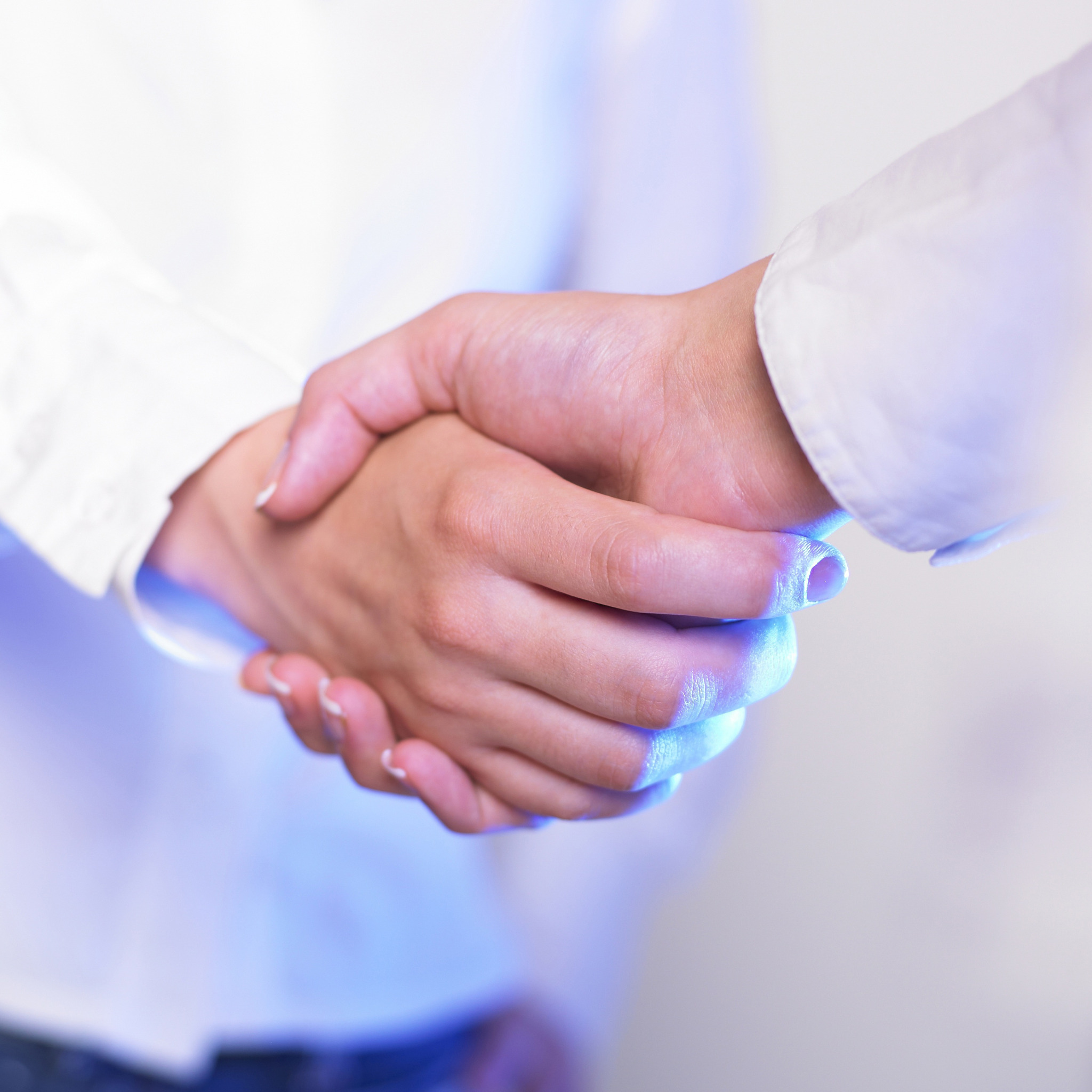 Uścisk dłoni na jasnym tle, symbolizujący zawarcie umowy lub partnerstwo biznesowe.
