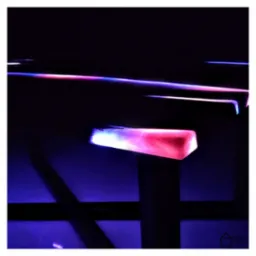 Podświetlony od spodu blat z żywicy epoksydowej w ciemnym pomieszczeniu, widoczne refleksy światła w kolorach różu i fioletu.