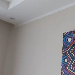 Jasnoszara ściana po remoncie z dekoracyjną listwą przysufitową i fragmentem kolorowego obrazu po prawej stronie.