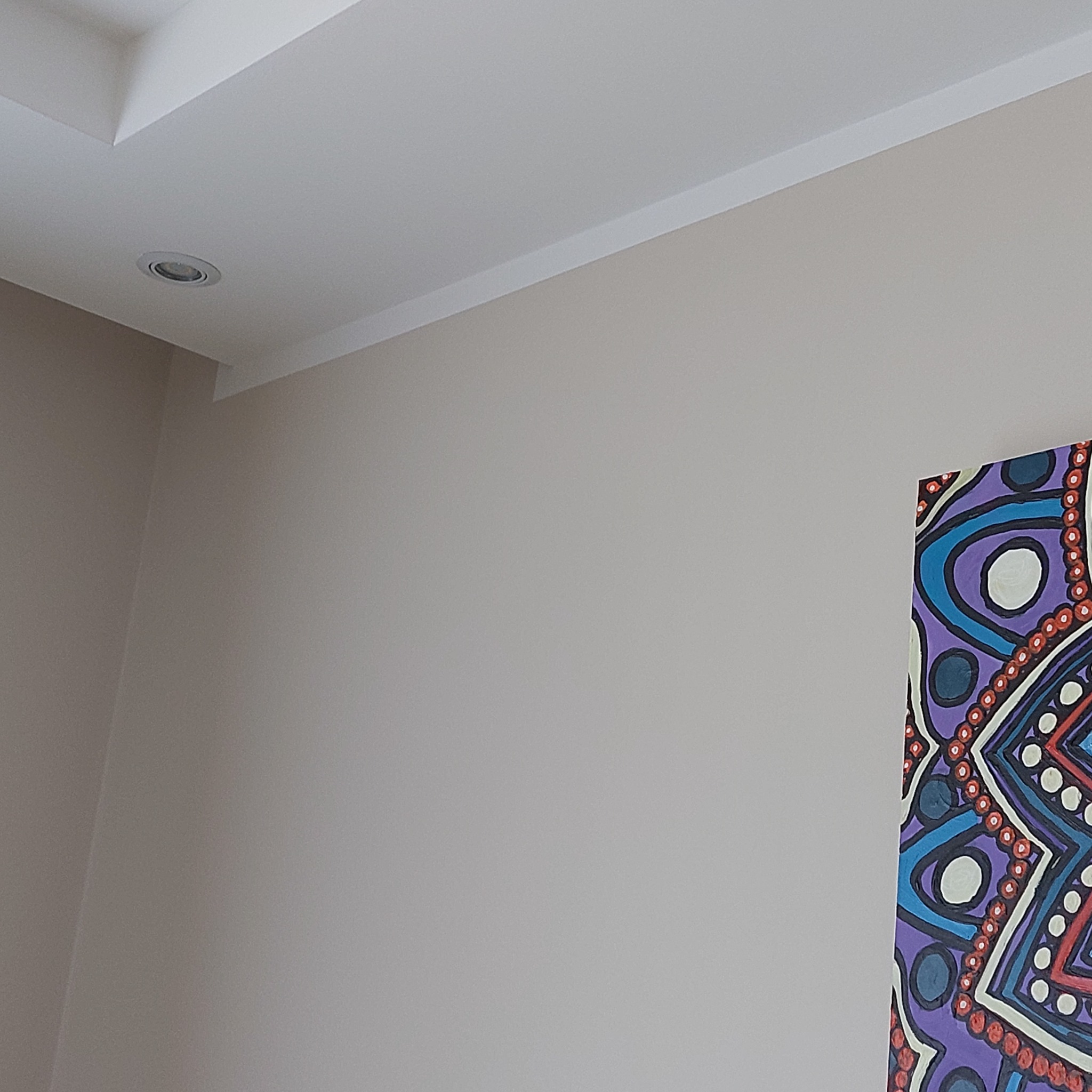 Jasnoszara ściana po remoncie z dekoracyjną listwą przysufitową i fragmentem kolorowego obrazu po prawej stronie.