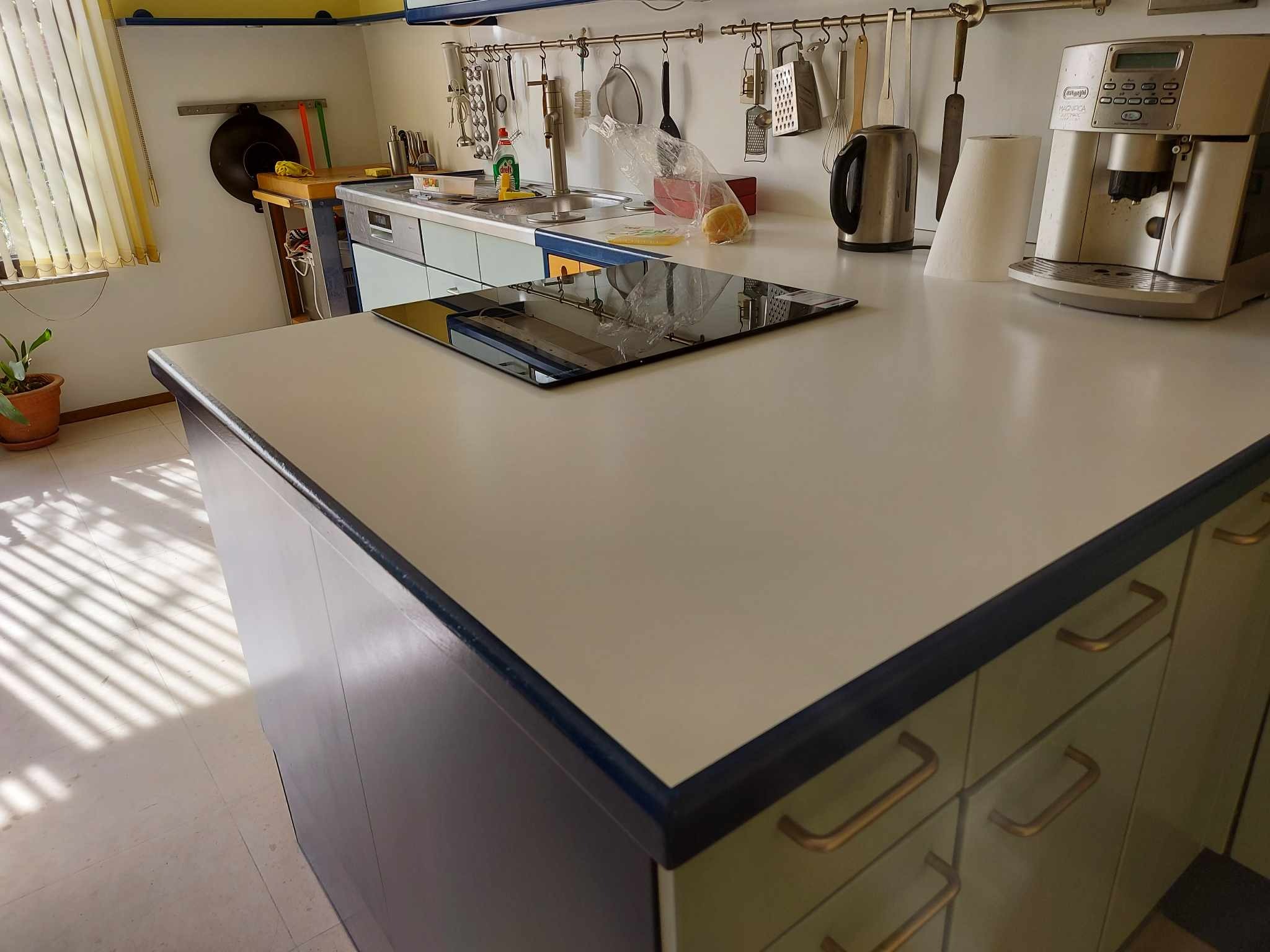 Wykończona zabudowa kuchenna z blatem i płytą indukcyjną w Zduńskiej Woli, widoczne akcesoria kuchenne i ekspres do kawy.