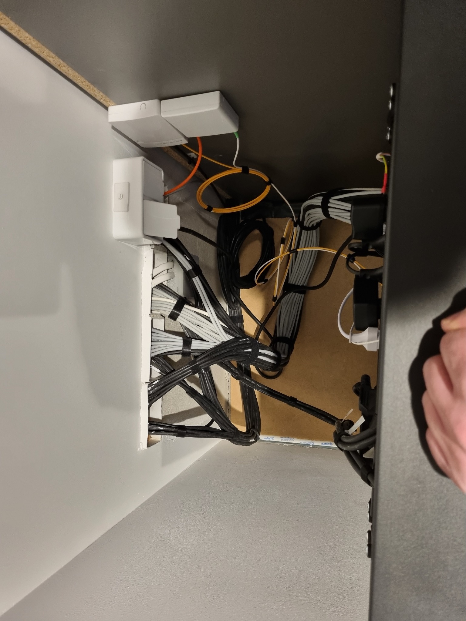 Uporządkowane kable elektryczne i światłowodowe w listwach przypodłogowych i puszkach instalacyjnych, widok z góry.