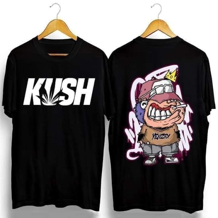 Dwie czarne koszulki na wieszakach. Na jednej biały napis 'KUSH' z motywem liścia, na drugiej kreskówkowa postać z papierosem i koroną.