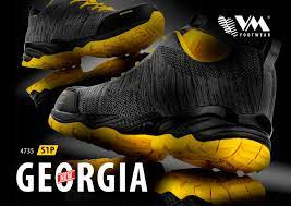 Dwa buty robocze z czarnego materiału z żółtymi akcentami na podeszwie i zapiętku, ułożone jeden na drugim, z widocznym logo producenta i nazwą modelu 'Georgia' na czarnym tle.