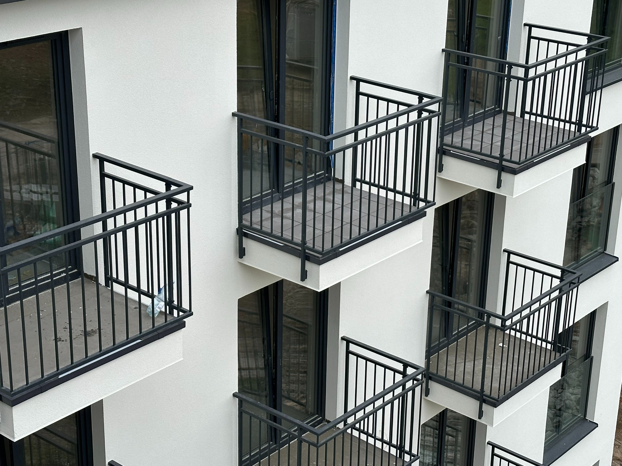 Elewacja budynku z balkonami z czarnymi, metalowymi balustradami, widok z dołu pod kątem.