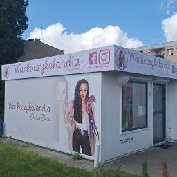 Bestprom Producent Reklam - Oklejony pawilon z reklamą salonu fryzjerskiego 'Warkoczykolandia' z wizerunkiem kobiety z warkoczami i danymi kontaktowymi. Widoczne logo i ikony mediów społecznościowych.