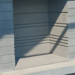 Szara murowana wnęka z półką, oświetlona ostrym cieniem, wykonana z podłużnych cegieł.