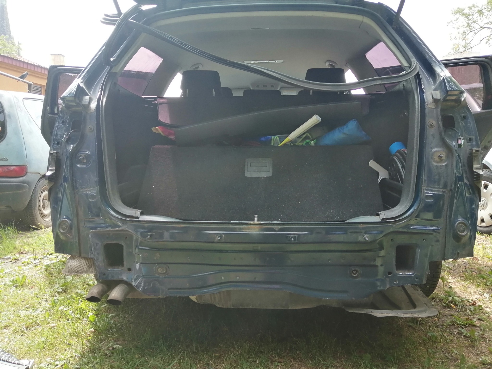 Uszkodzony tył samochodu kombi z otwartą klapą bagażnika, widoczne elementy konstrukcyjne i wnętrze bagażnika z różnymi przedmiotami w Olsztynie.