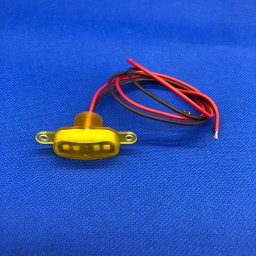 Serious Engineering - Żółta dioda LED z przewodami czerwonym i czarnym leżąca na niebieskim tle.