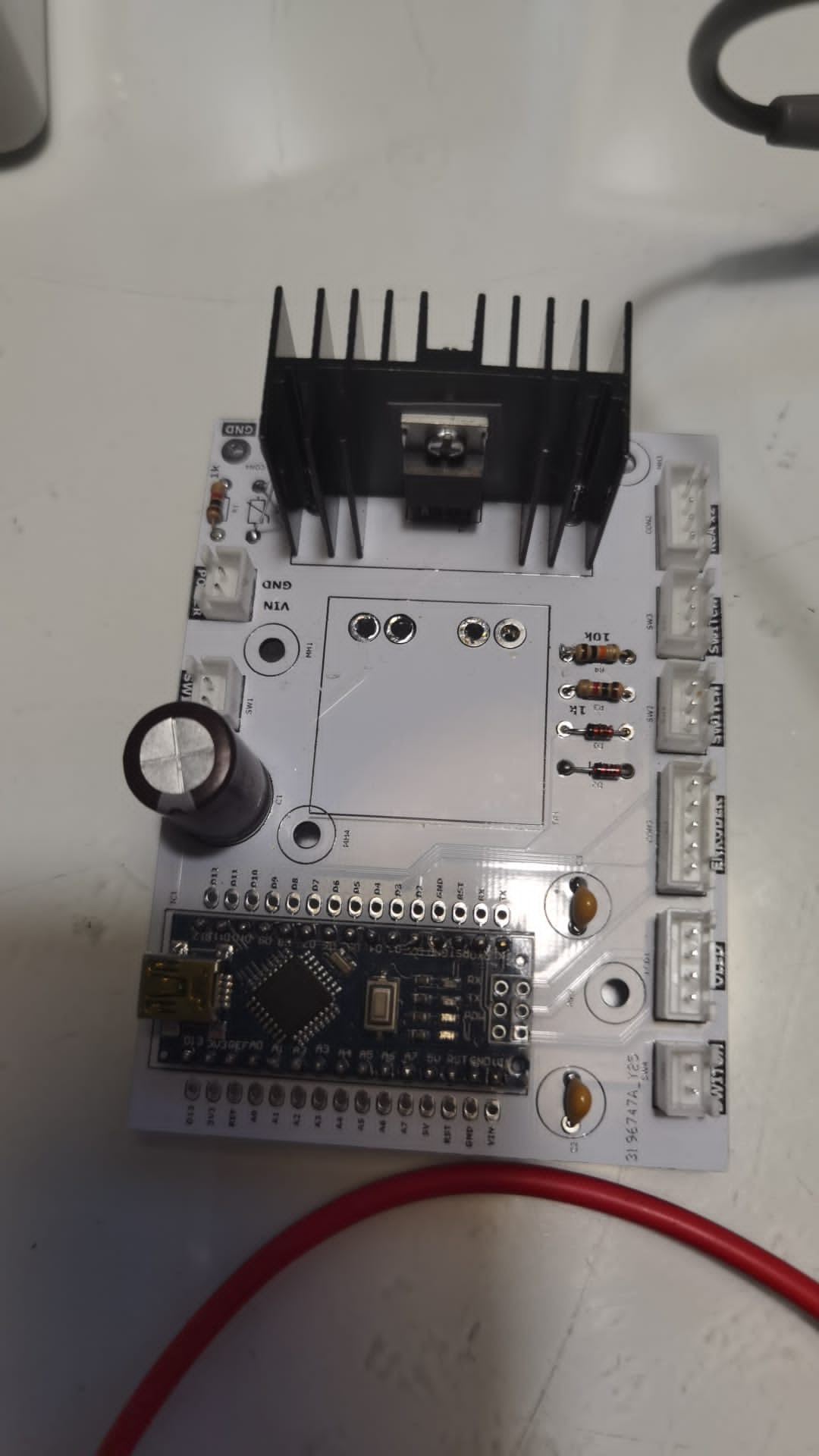 Płytka prototypowa z mikrokontrolerem Arduino Nano i radiatorem, widoczna z bliska, elementy elektroniczne na białym tle, realizacja projektu w Poznaniu.