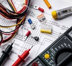 Multimetr, przewody elektryczne, złączki WAGO i schemat instalacji elektrycznej na białym tle. Widoczne końcówki kablowe i próbnik napięcia.