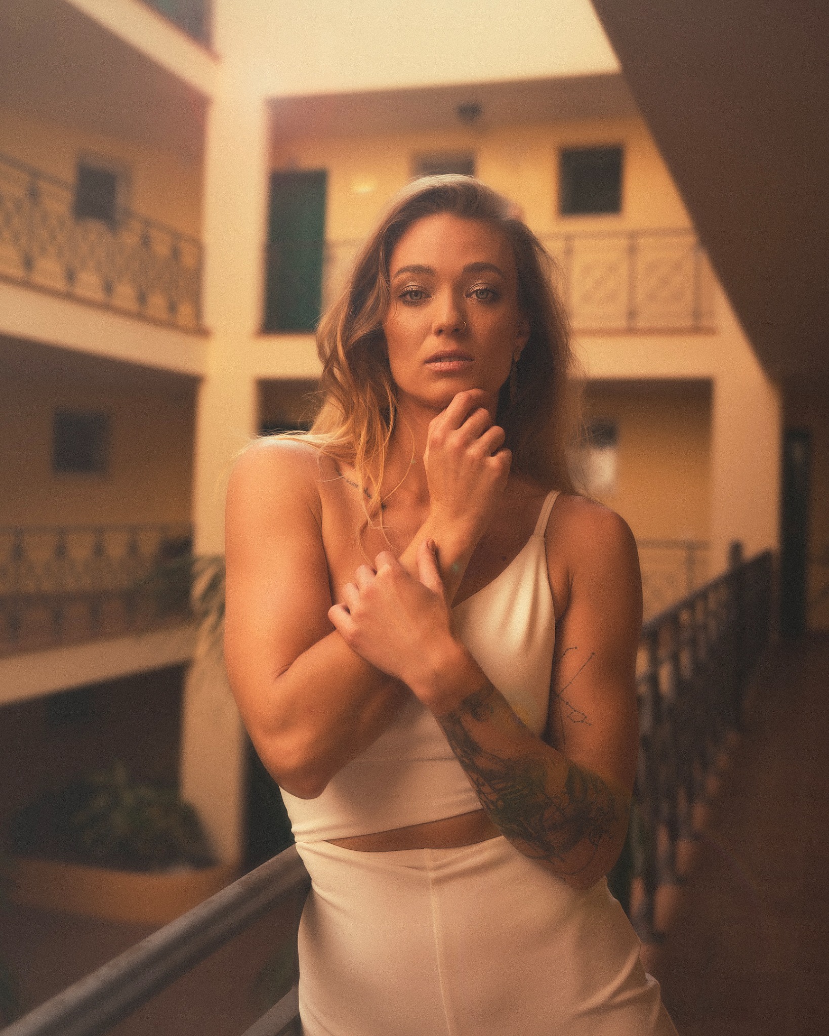 Portret kobiety z tatuażami na ramieniu, pozującej na tle hotelowego balkonu na Teneryfie.