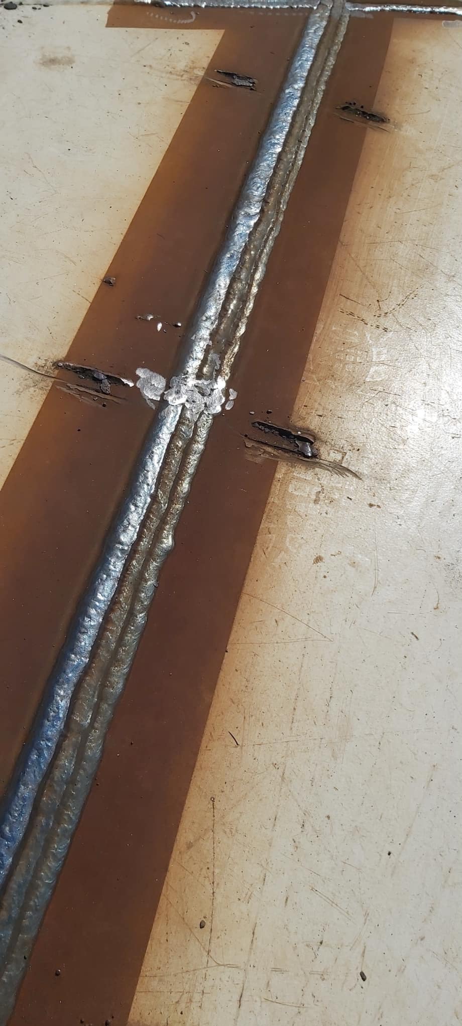 Spoina spawalnicza na metalowej powierzchni z widocznymi śladami po spawaniu i zabrudzeniami.