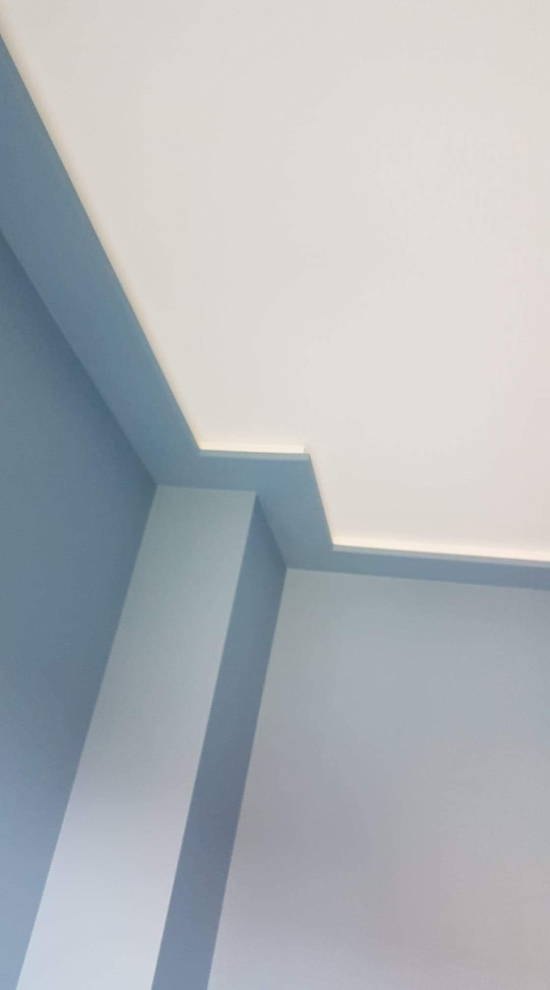 Pomieszczenie po malowaniu: biały sufit z dekoracyjnym, podświetlonym obramowaniem w odcieniach błękitu, błękitne ściany.