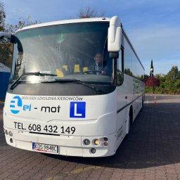 El-Mot Jan cempiel - Biały autobus z napisem 'Ośrodek Szkolenia Kierowców el-mot' i niebieską literą 'L' na parkingu, widok z przodu na kierowcę za szybą.