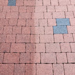 CleanTech - Ułożona kostka brukowa w odcieniach czerwieni z wkomponowanymi szarymi kostkami, widoczne różnice w odcieniach spowodowane prawdopodobnie wilgocią lub różnym stopniem zabrudzenia.