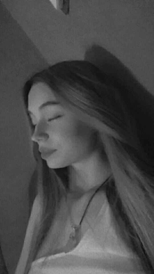 Portret młodej kobiety z długimi włosami, profil, czarno-białe zdjęcie w miękkim świetle.