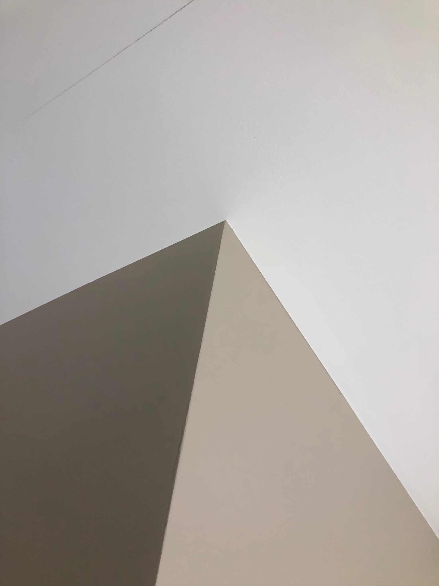 Fragment pomalowanego narożnika sufitu i ścian w odcieniach bieli i beżu. Widoczne delikatne przejścia kolorystyczne i gładka powierzchnia.