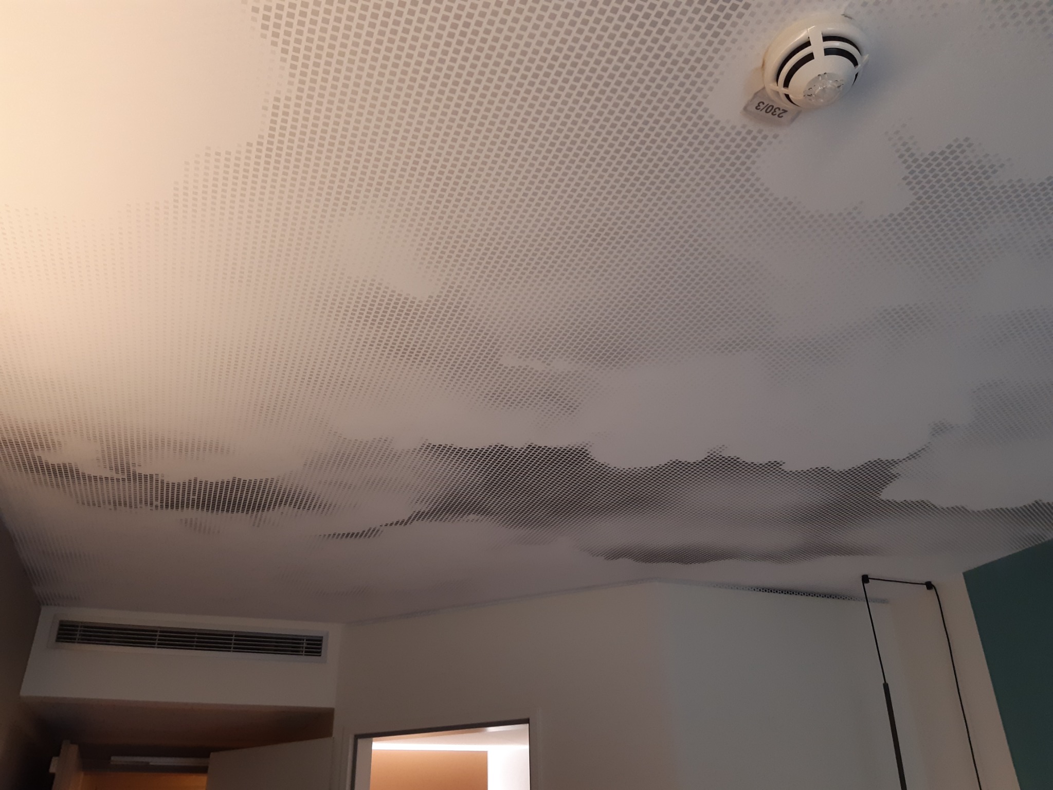 Sufit napinany z nadrukiem chmur w pokoju w Sulechowie, widoczny czujnik dymu i kratka wentylacyjna.