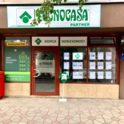 Fasada biura Agencji Nieruchomości Tecnocasa z zielonym logo, adres Grabiszyńska 92A, ogłoszenia w oknach i czerwona skrzynka pocztowa obok wejścia.
